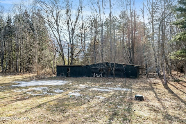 view of yard with a pole building, an outdoor structure, and a view of trees