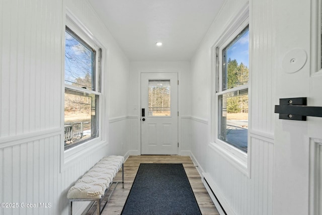 doorway featuring wood finished floors and wainscoting