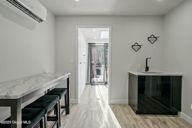 bar featuring light wood-style flooring, recessed lighting, a sink, baseboards, and an AC wall unit