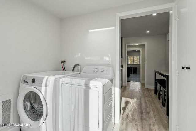 clothes washing area with baseboards, laundry area, wood finished floors, and washer and dryer