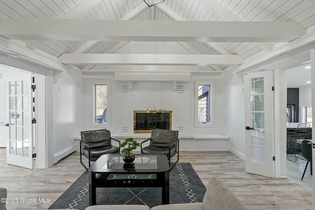 living area with lofted ceiling with beams, a baseboard radiator, a fireplace, french doors, and light wood-type flooring