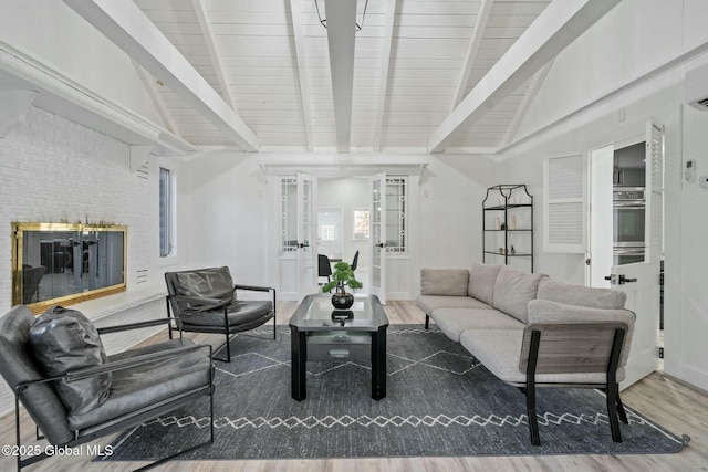 living room featuring lofted ceiling with beams, a brick fireplace, and wood finished floors