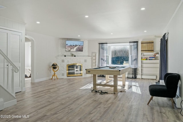 game room with arched walkways, recessed lighting, a high end fireplace, wood finished floors, and baseboards