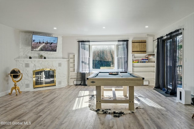 playroom featuring pool table, crown molding, wood finished floors, and a stone fireplace