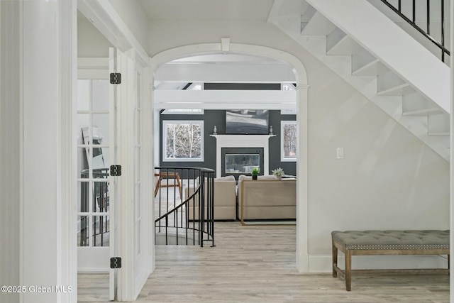 interior space featuring stairs, a glass covered fireplace, and wood finished floors