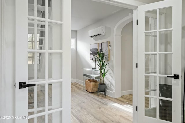 entryway featuring arched walkways, wood finished floors, baseboards, french doors, and a wall mounted AC