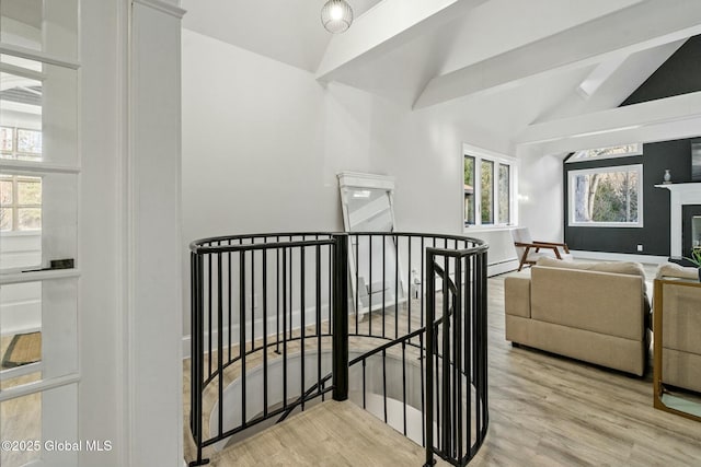 stairway featuring a glass covered fireplace, vaulted ceiling, and wood finished floors