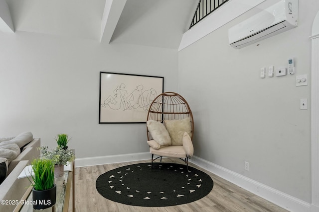 sitting room with an AC wall unit, baseboards, and wood finished floors