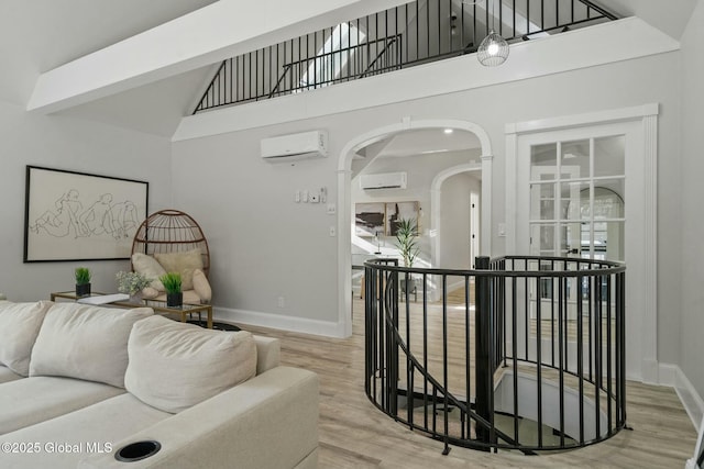 interior space featuring baseboards, arched walkways, an AC wall unit, and wood finished floors