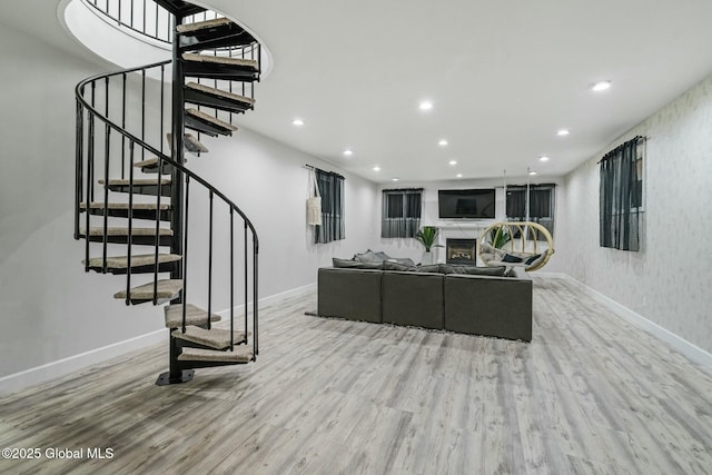 living area featuring recessed lighting, stairway, wood finished floors, and a glass covered fireplace