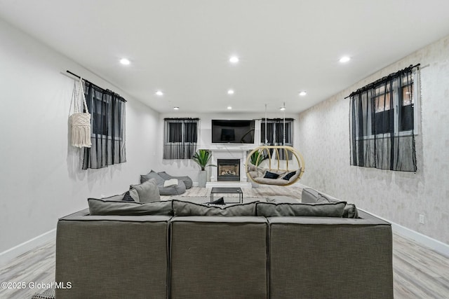 living area with baseboards, light wood finished floors, a high end fireplace, and recessed lighting