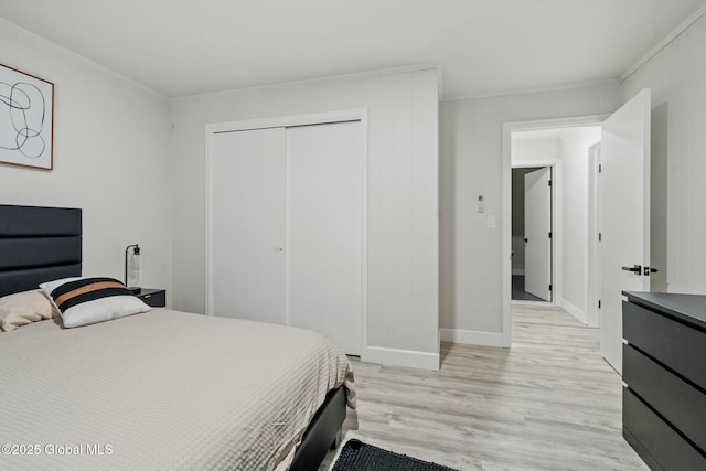 bedroom with ornamental molding, light wood-type flooring, a closet, and baseboards