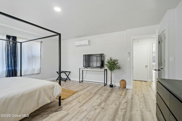 bedroom with light wood-style floors, an AC wall unit, and baseboards