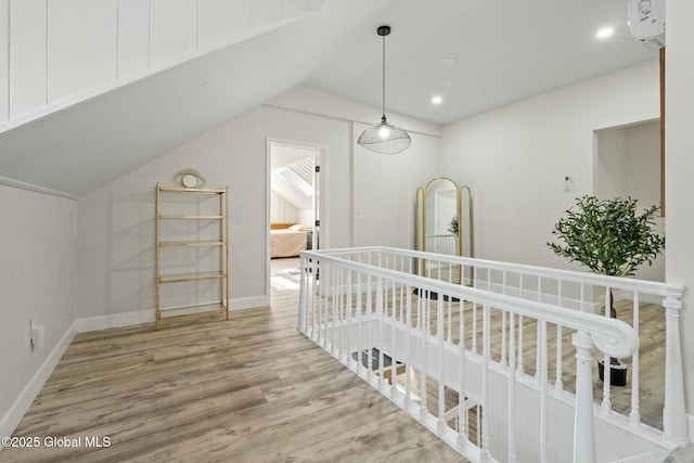 interior space featuring baseboards, lofted ceiling, wood finished floors, a wall mounted air conditioner, and recessed lighting