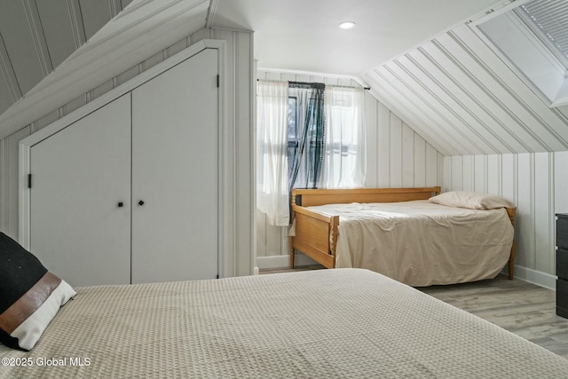 bedroom with lofted ceiling, a closet, recessed lighting, and wood finished floors