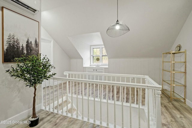 bonus room featuring vaulted ceiling, a wall mounted air conditioner, wood finished floors, and baseboards