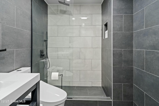 bathroom featuring a tile shower, vanity, and toilet