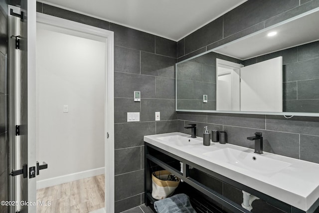 bathroom with tile walls, a sink, and wood finished floors