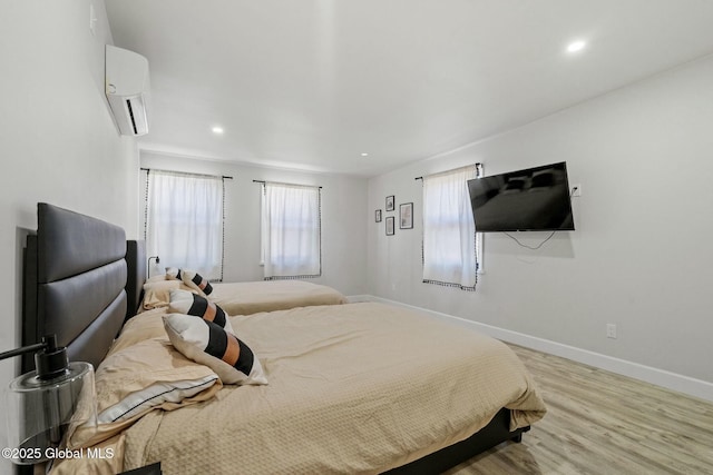 bedroom featuring recessed lighting, a wall unit AC, wood finished floors, and baseboards