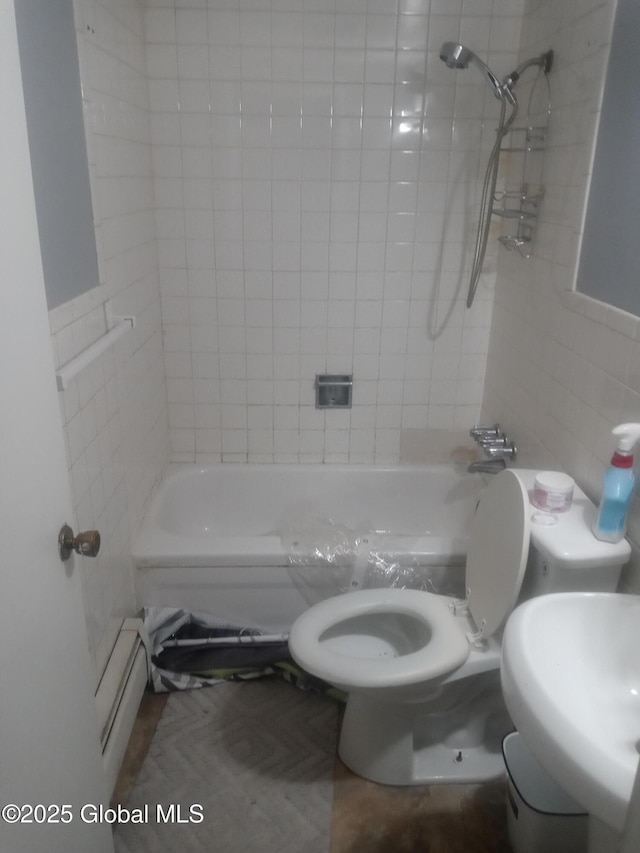 bathroom with tile walls, toilet, shower / tub combination, and a sink