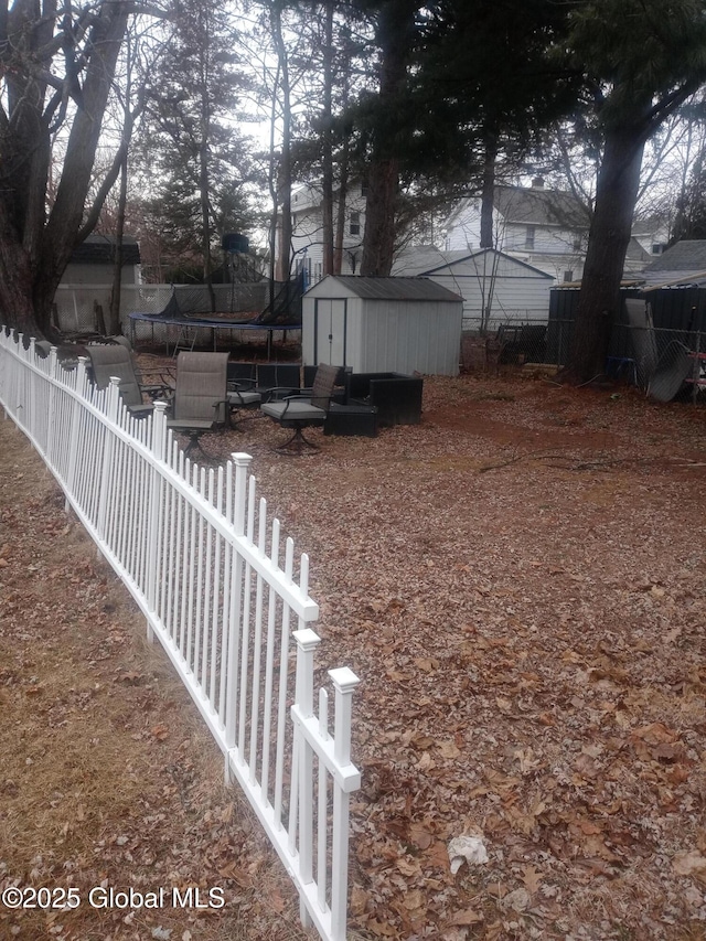 view of yard featuring a storage shed, a trampoline, fence, and an outdoor structure