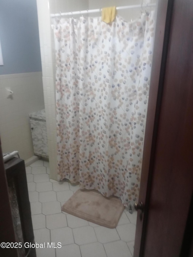 bathroom featuring tile patterned flooring, wainscoting, tile walls, and a shower with shower curtain