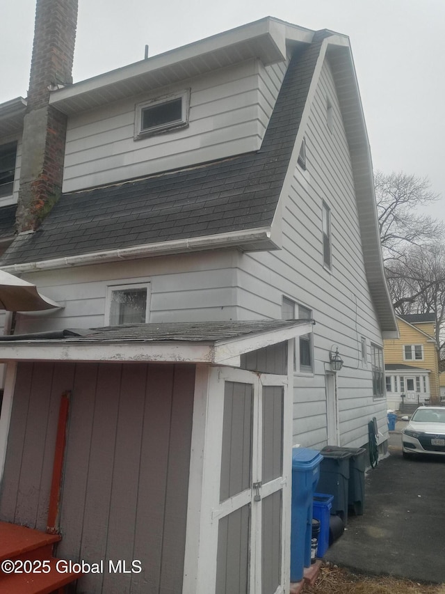 view of property exterior with a chimney and roof with shingles