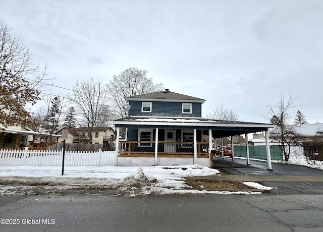 view of front of house with covered porch, fence, and a carport