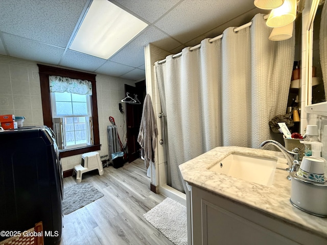 full bath with a paneled ceiling, a shower stall, vanity, and wood finished floors