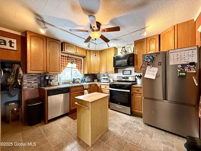 kitchen featuring ceiling fan, a textured ceiling, stainless steel appliances, a sink, and backsplash