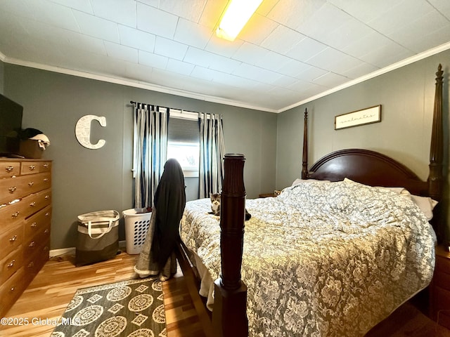 bedroom with ornamental molding and wood finished floors