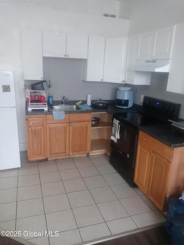 kitchen with dark countertops, visible vents, black range with electric stovetop, under cabinet range hood, and freestanding refrigerator