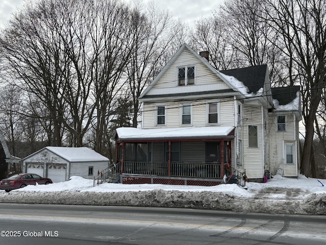 view of front of house with covered porch, a chimney, an outbuilding, and a detached garage