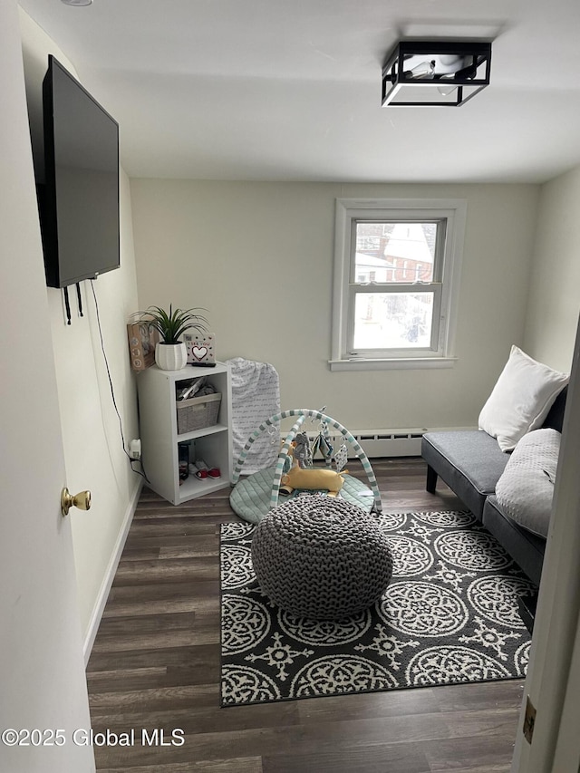 living area featuring baseboards, baseboard heating, and wood finished floors