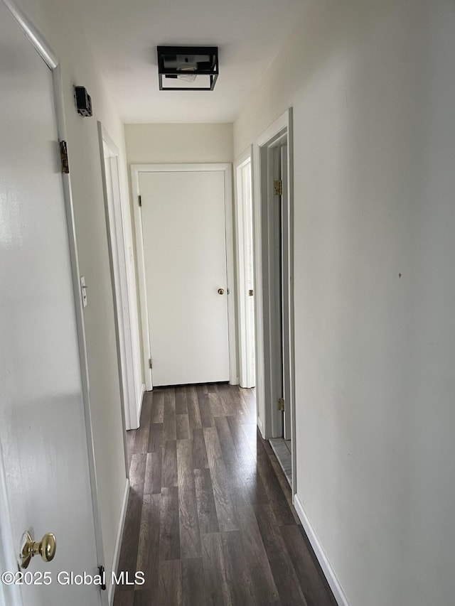 corridor with dark wood-style flooring and baseboards