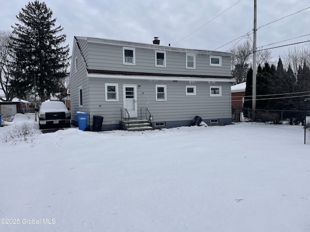 snow covered rear of property featuring fence