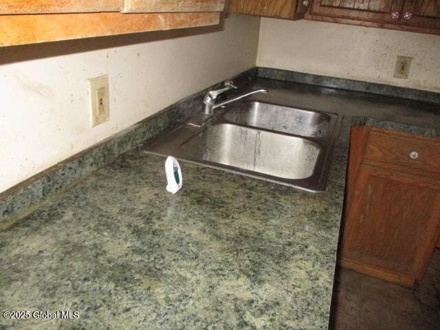 details with brown cabinetry, dark countertops, and a sink