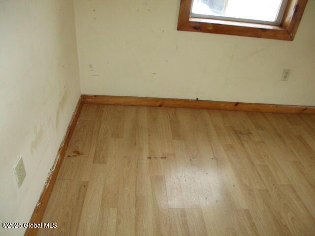 spare room featuring baseboards and wood finished floors