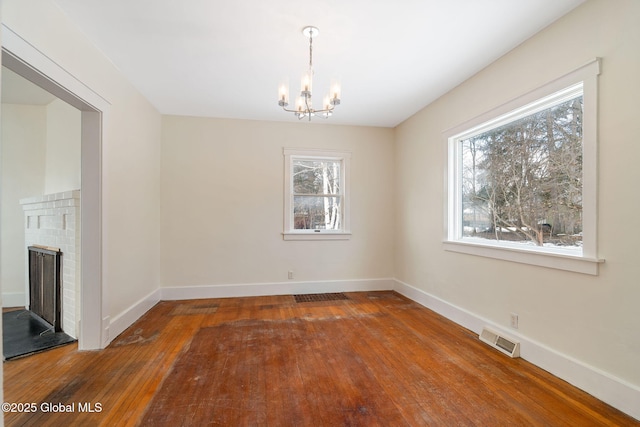 interior space featuring a brick fireplace, visible vents, baseboards, and hardwood / wood-style flooring