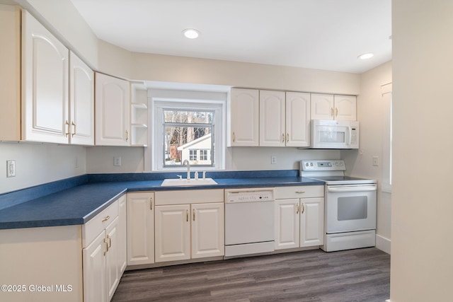 kitchen featuring white appliances, dark countertops, dark wood-type flooring, white cabinetry, and a sink