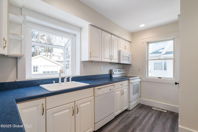 kitchen featuring white appliances, visible vents, white cabinets, dark countertops, and a sink