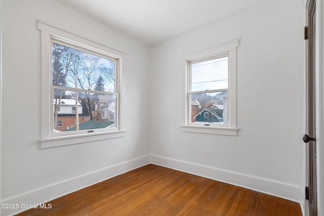 spare room featuring baseboards and wood finished floors