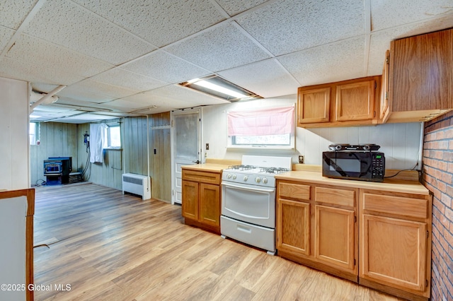 244 Kingsboro Ave, Gloversville, NY 12078 - kitchen featuring gas range, radiator, black microwave, a drop ceiling, and a wood stove