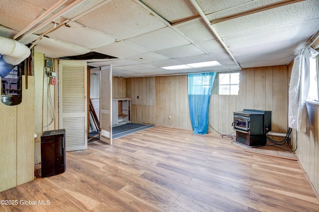 244 Kingsboro Ave, Gloversville, NY 12078 - below grade area featuring a wood stove, wood walls, wood finished floors, and a paneled ceiling