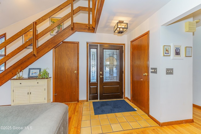 entrance foyer featuring light wood-type flooring, stairway, and baseboards