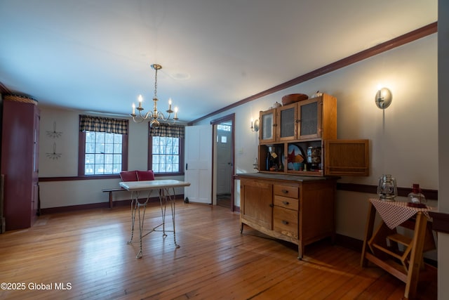 dining area with a notable chandelier, baseboards, light wood-style floors, and ornamental molding