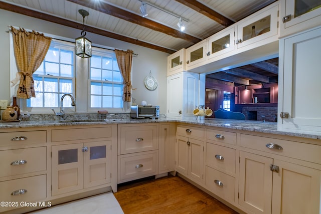 kitchen featuring beam ceiling, a sink, light wood-style floors, wood ceiling, and hanging light fixtures