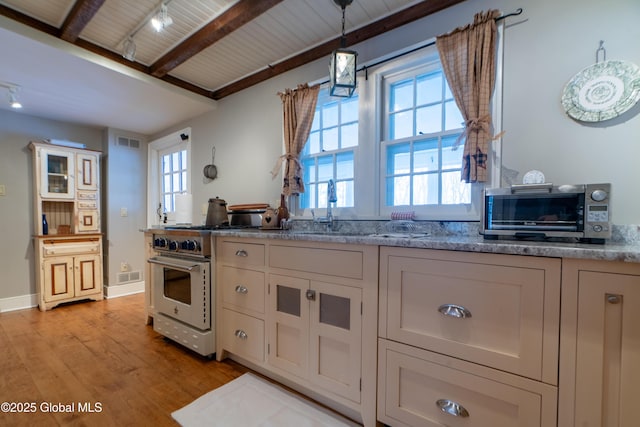 kitchen featuring a sink, light wood-style floors, visible vents, and high end stainless steel range