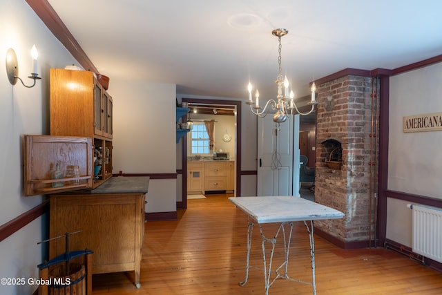 dining area featuring baseboards, radiator heating unit, an inviting chandelier, and wood-type flooring