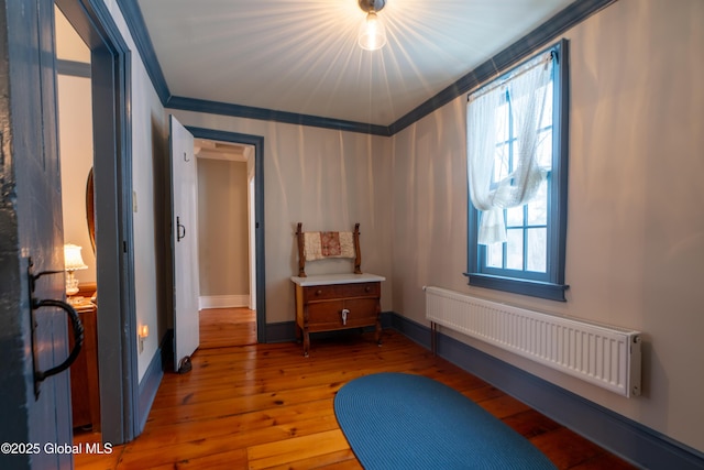 interior space featuring hardwood / wood-style flooring, radiator, baseboards, and ornamental molding